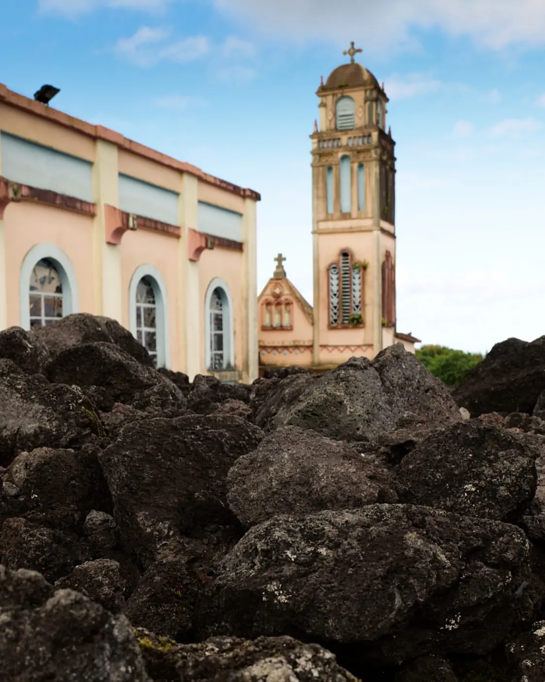 Façade rose de l'église Notre-Dame des Laves entourée de lave solidifiée, Piton Sainte-Rose, La Réunion